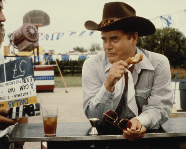 Larry Hagman on the set of Dallas eating fried chicken in a cowboy hat.