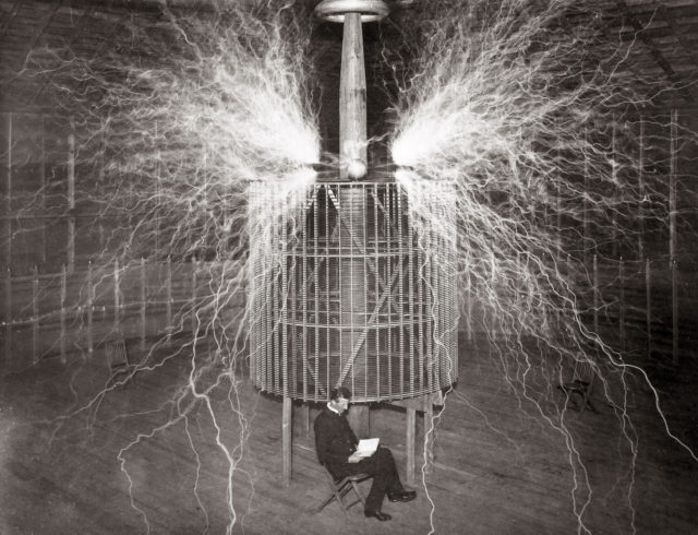 Nikola Tesla sitting with his "Magnifying Transmitter"