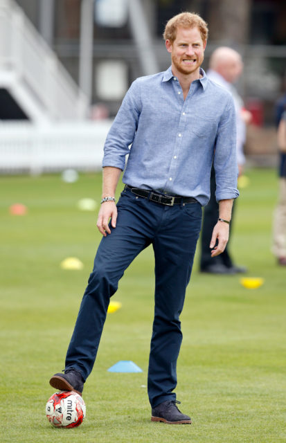 Prince Harry resting his foot on a soccer ball