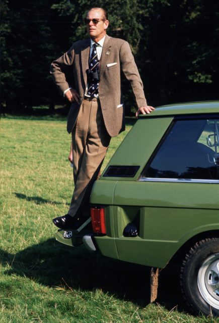 Prince Philip standing on the back of his Range Rover