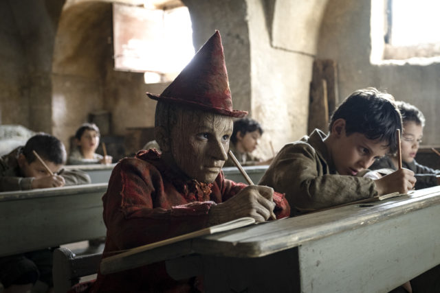 Pinocchio sits at a desk in a classroom