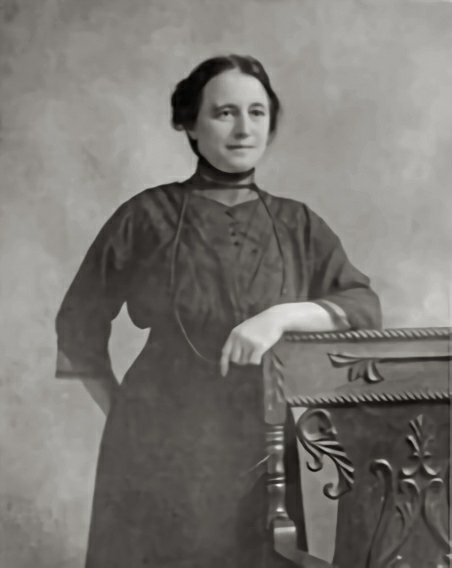 Portrait of Rhoda Mary Abbott posed in front of chair.