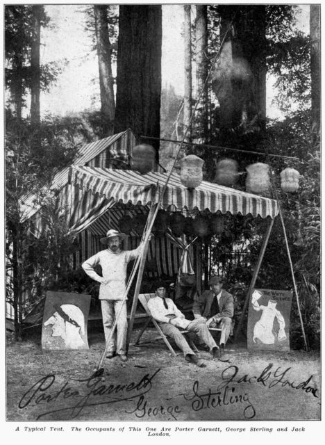 A tent at Bohemian Grove with three men sitting underneath