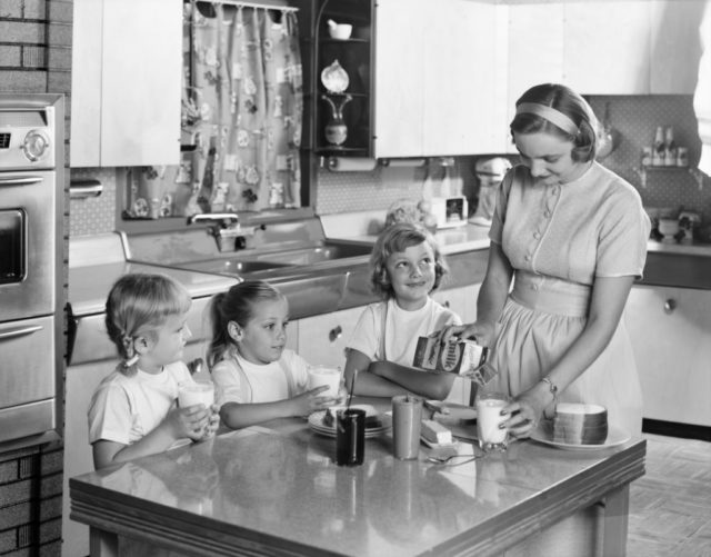 A family sits at a table making peanut butter sandwiches