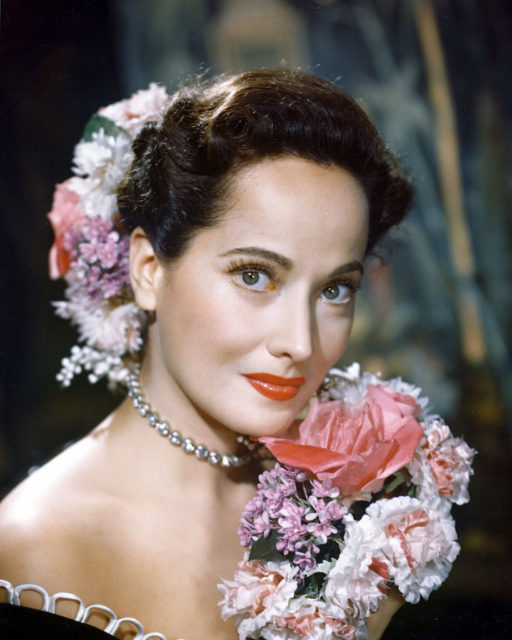 Portrait of Merle Oberon holding flowers.