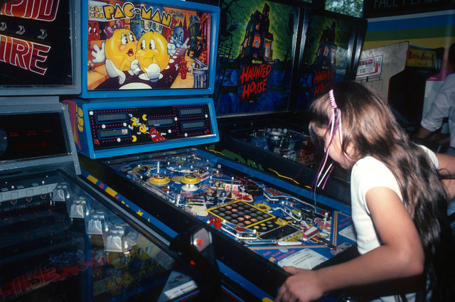 A child plays a Pac Man game at an arcade.