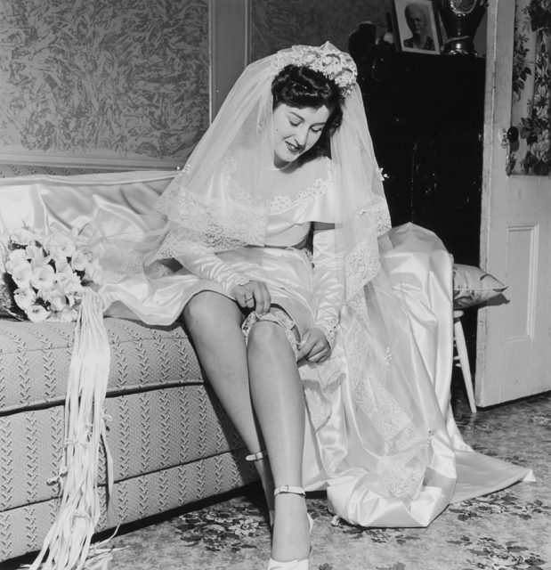 Bride pulling a garter over her leg before wedding ceremony