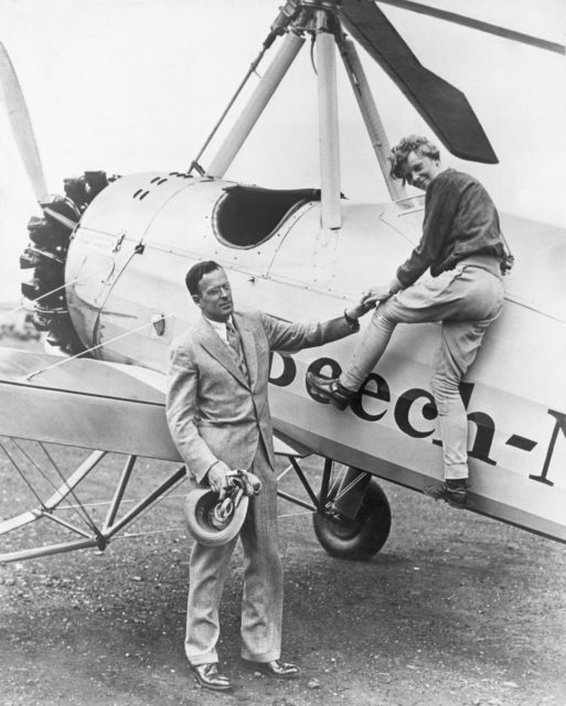 Amelia Earhart getting out of her plane with the help of her husband, George Putnam