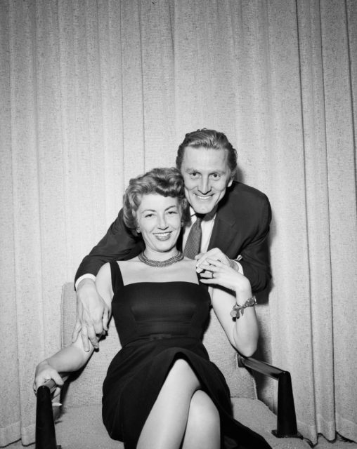 Anne Douglas sitting on a chair, with Kirk Douglas smiling behind her