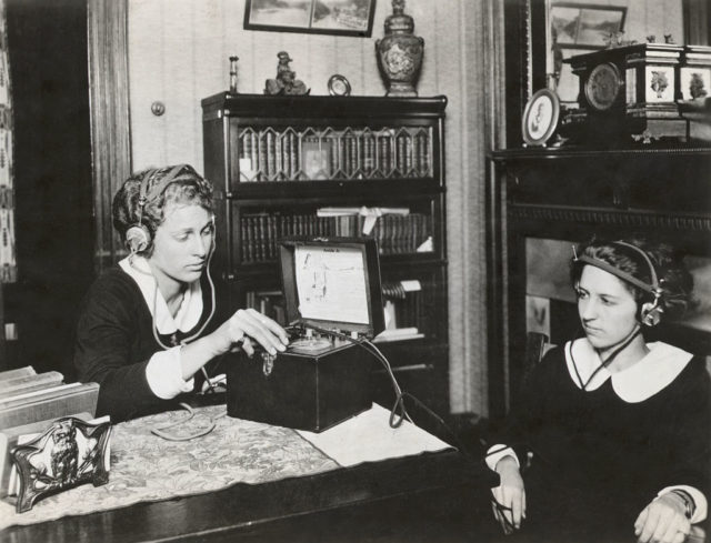 Two women listening to a radio