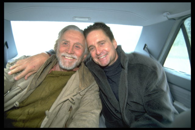 Kirk and Michael Douglas smiling in the back of a car