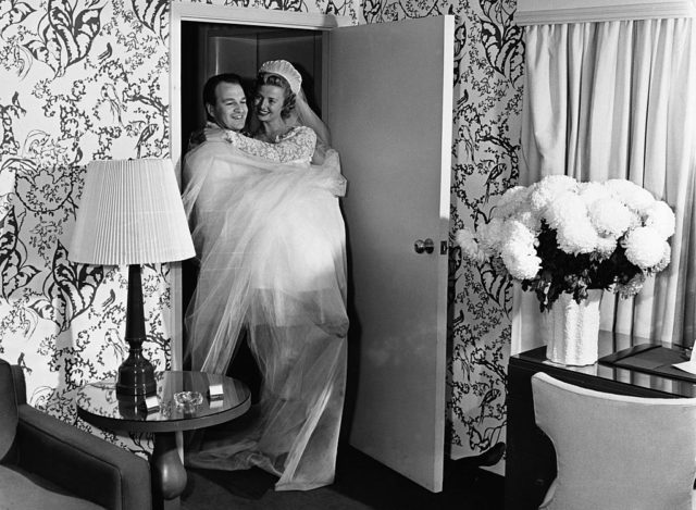 Groom carries his bride across the threshold of their home.