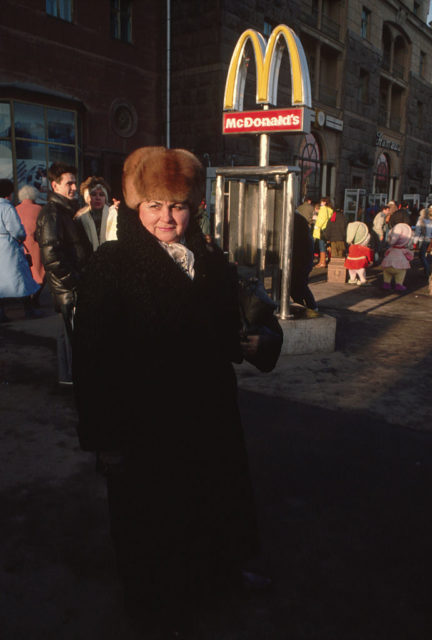 A woman stands by a McDonald's sign