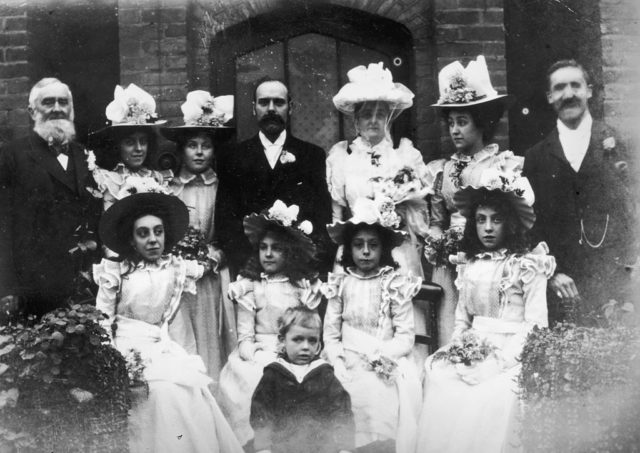 A large wedding party poses outside a church in 1897