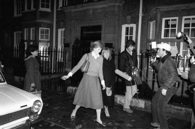 Princess Diana walking along the street, surrounded by paparazzi