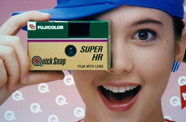 A girl holding a disposable camera