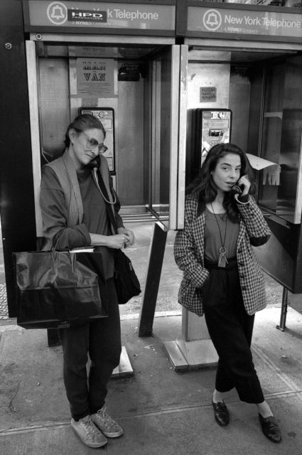 Black and white photo of 2 women using payphones