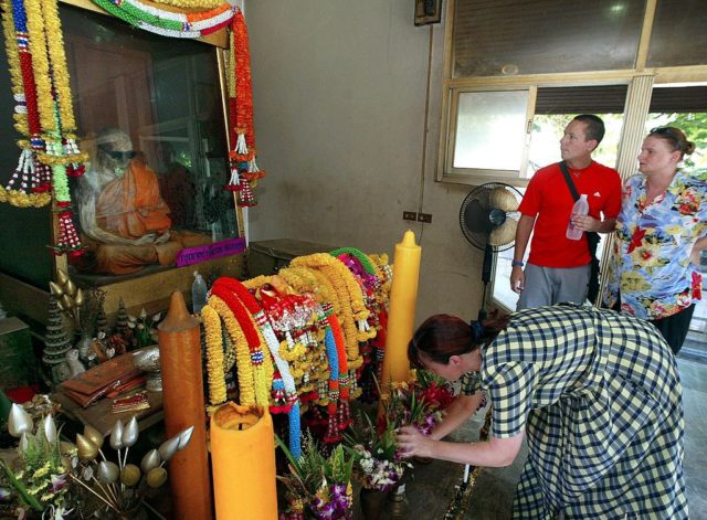 Visitors looking at the mummified body of a monk 