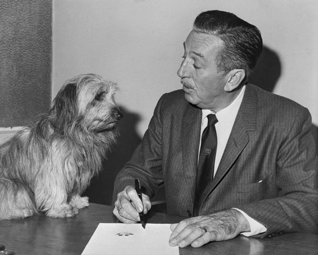 Walt Disney sitting with a dog 