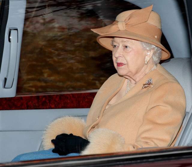 Queen Elizabeth wears a beige-colored outfit with faux fur accents.