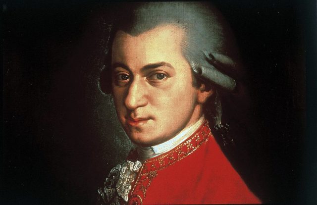Coloured painting of Mozart in a white wig with curls and a red jacket.