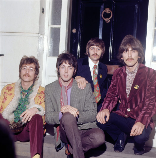 The beatles sitting outside a house