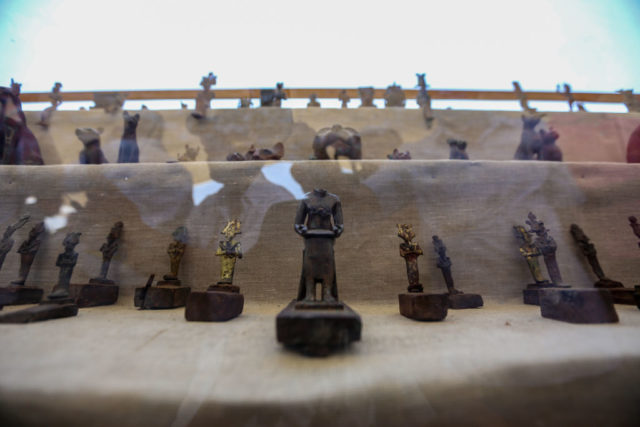 Statues of Egyptian deities displayed behind a glass case