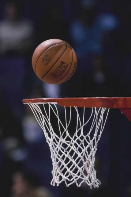 Basketball mid-air above a basketball hoop