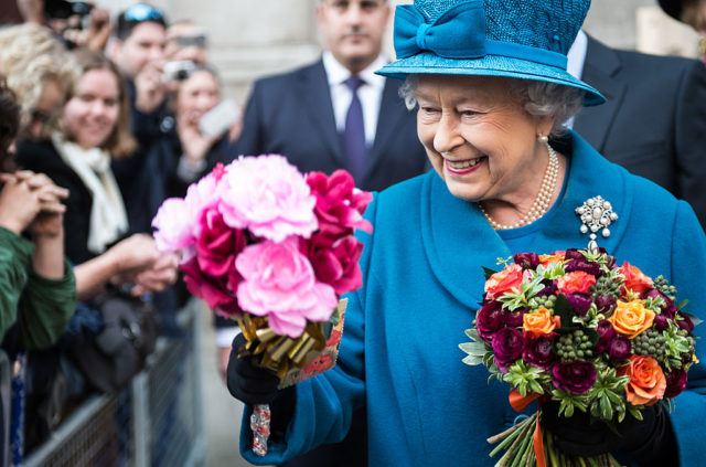 Queen Elizabeth II holding two bouquets of flowers