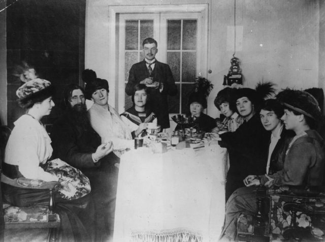 Rasputin and ladies sitting around a table, Tsar Nicholas II standing at the head