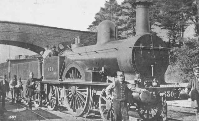 Men pose with a locomotive engine
