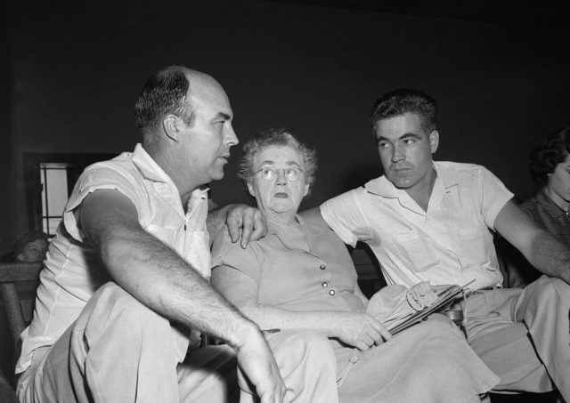 Black and white photo of two men with their arms around an older woman, their mother.