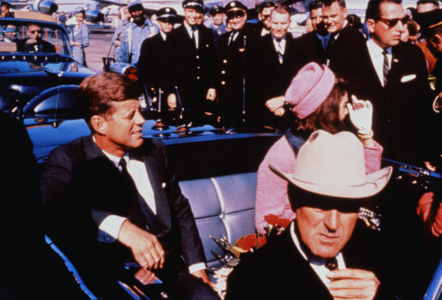 John F. and Jackie Kennedy seated in the back of an open top car