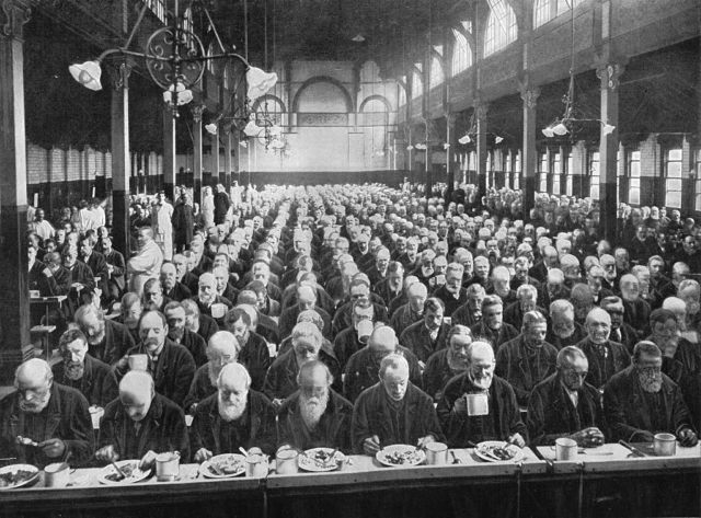 Rows of workers eat dinner at a workhouse