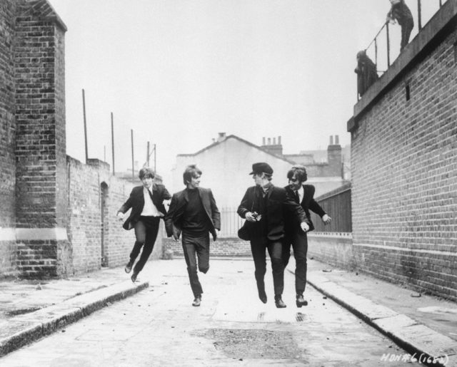 The Beatles running down a street