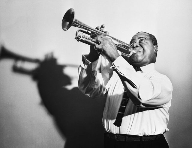 Louis Armstrong poses with his trumpet.