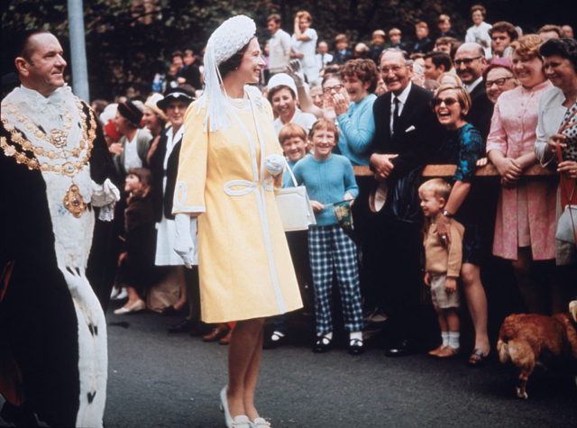 Queen Elizabeth II wears a yellow dress and beaded hat while visiting Australia.