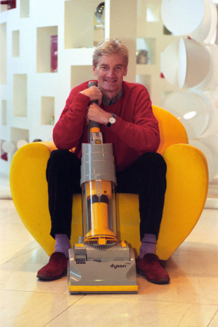 James Dyson poses with a Dyson vacuum he designed. 