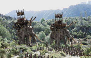 Movie still of two elephants walking through a field with riding equipment on from Lord of the Rings
