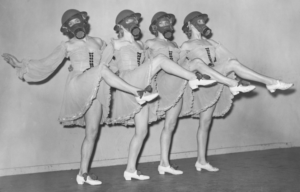 Four Windmill girls performing in gas masks