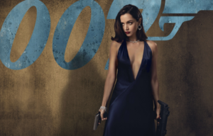 Colored movie still of Ana de Armas as Paloma holding two guns and wearing and royal blue dress with a plunging neckline.