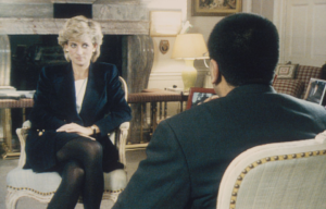 Colored photo of Diana in a black jacket sitting in front an interviewer, who appears with just the back of his head in a suit jacket.