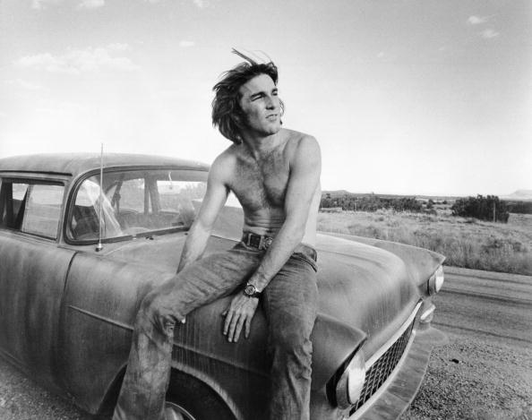 Dennis Wilson sitting on the hood of a car