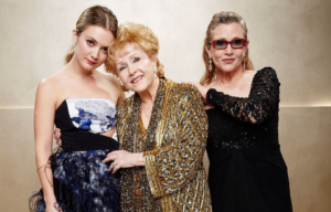 Billie Lourd is embraced by grandmother Debbie Reynolds and mother Carrie Fisher at a special event