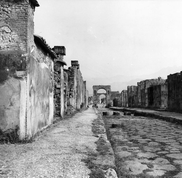Black and white photo of a ruined street in Pompeii after the volcano erupted. 