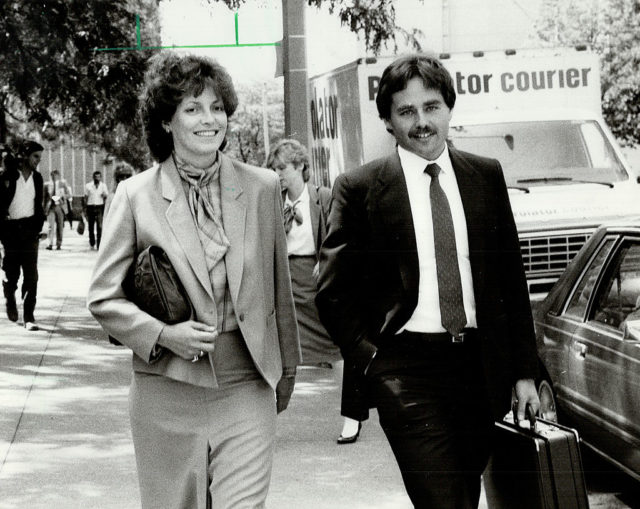 Black and white photo of Cathy smith in a pantsuit walking beside a man in a black suit.