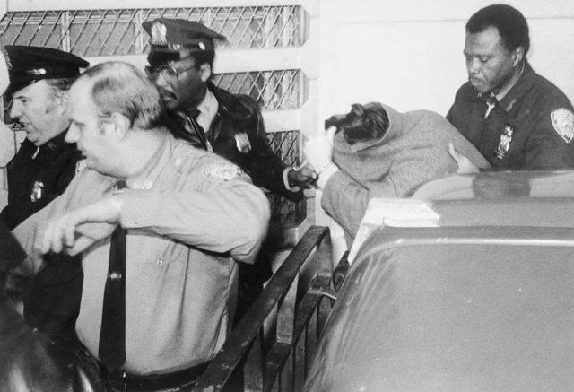 Mark David Chapman covers his face while exiting car