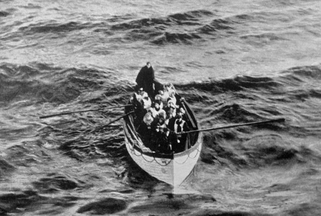 Black and white photo of people in a lifeboat from the Titanic on the water.