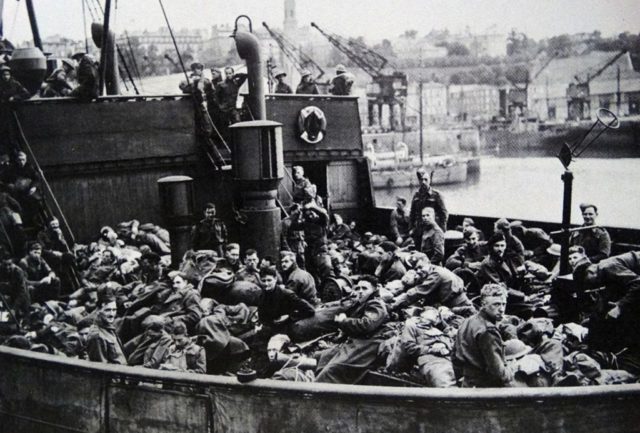 Black and white photo of a large number of soldiers lying down on a boat.