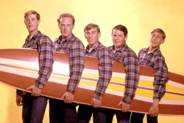 The Beach Boys holding a surfboard